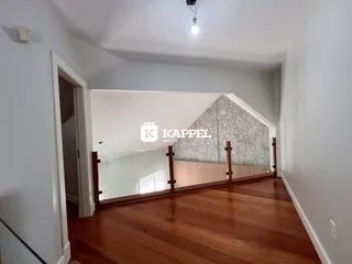 Vista de um ambiente interno com piso de madeira e parede de pedra aparente.