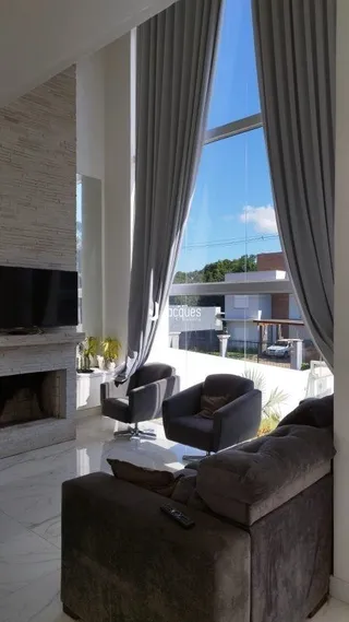 Vista interna de uma sala com grandes janelas e cortinas em Lajeado.