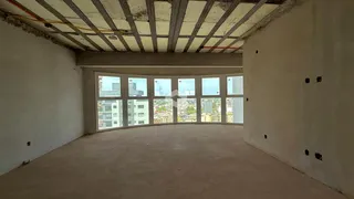 Espaço interno com teto de estrutura aparente e vista para a cidade.