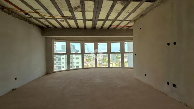 Espaço interno com teto de estrutura aparente e vista para a cidade.