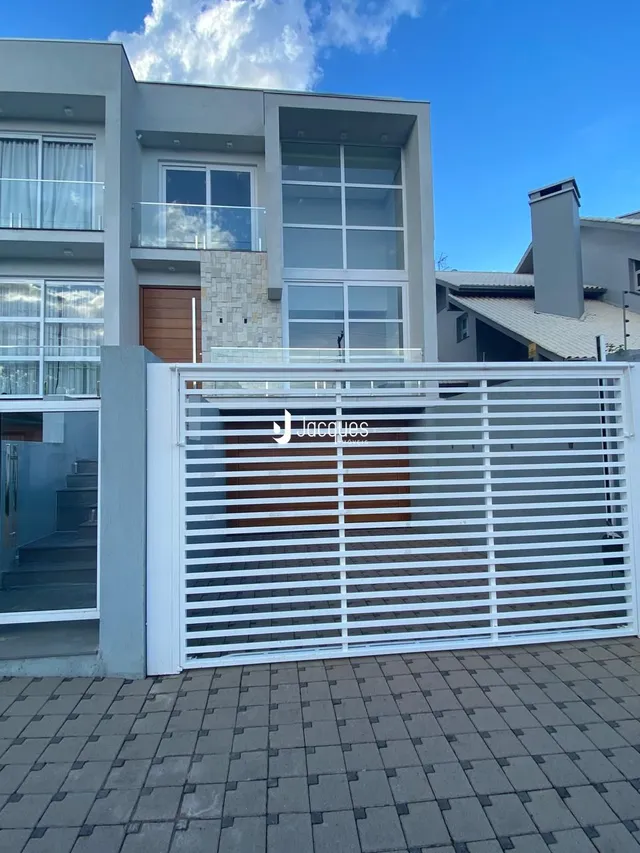 Fachada moderna de uma residência em Lajeado, Brasil, com portão branco.