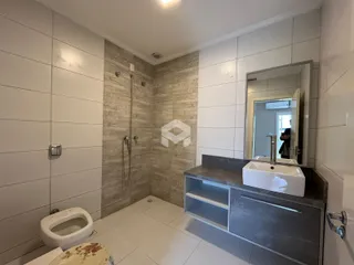 Foto interna de um banheiro moderno com revestimento de cerâmica clara.