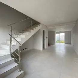 Hall de entrada com escadaria e piso claro.