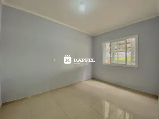 Uma sala de estar com paredes cinza claro e piso de cerâmica é visível na foto.