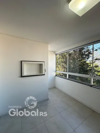 Interior de uma sala com paredes brancas e grande janela.