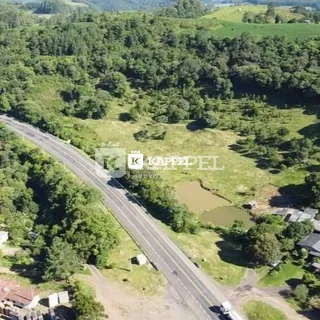 Vista aérea de uma área rural com vegetação densa e uma estrada.