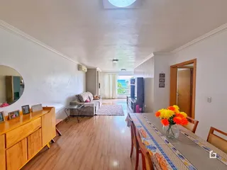 Sala de estar com piso de madeira e mesa de jantar em um imóvel no Brasil.