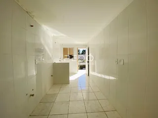Corredor interno de uma residência com piso de cerâmica clara.