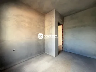 Interior de um cômodo com paredes de concreto aparente e piso cru.