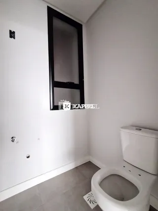 Foto de um banheiro interno mostrando um vaso sanitário branco e uma parede clara.