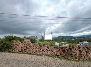 Vista externa de uma propriedade com muro de tijolos e paisagem montanhosa ao fundo.