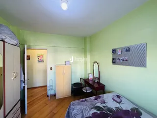 Quarto com paredes verdes e piso de madeira.