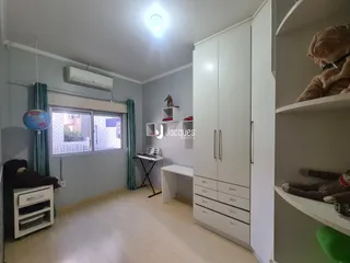 Sala de estar com paredes cinzas e piso de madeira clara em um imóvel no Brasil.