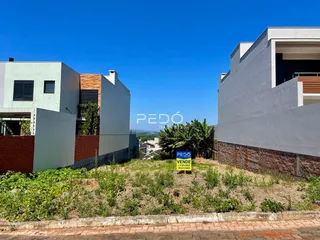 Fachada de duas construções residenciais em Lajeado, Brasil, com vegetação no primeiro plano.