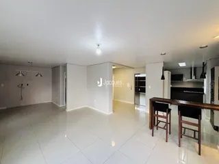 Sala de estar ampla com piso de cerâmica clara e paredes brancas.