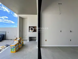 Foto de uma área interna em construção com paredes brancas e piso de concreto.