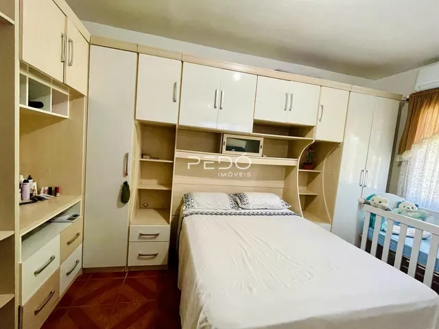 Quarto com armários brancos e cabeceira de madeira.