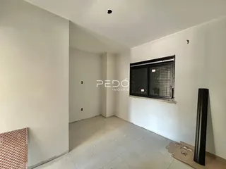 Interior de um ambiente com paredes brancas e piso de concreto.