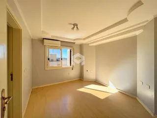 Ambiente interno com piso de madeira clara e molduras de teto.