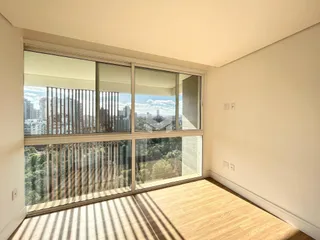 Vista de uma sala com piso de madeira e grandes janelas que dão para a paisagem.
