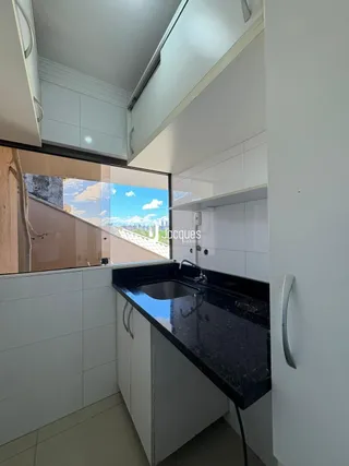 Interior da cozinha com armários brancos e vista externa.