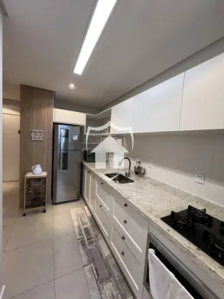 Vista da cozinha moderna com armários brancos e bancadas claras.