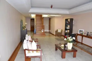 Sala de estar com piso de madeira e escadaria.