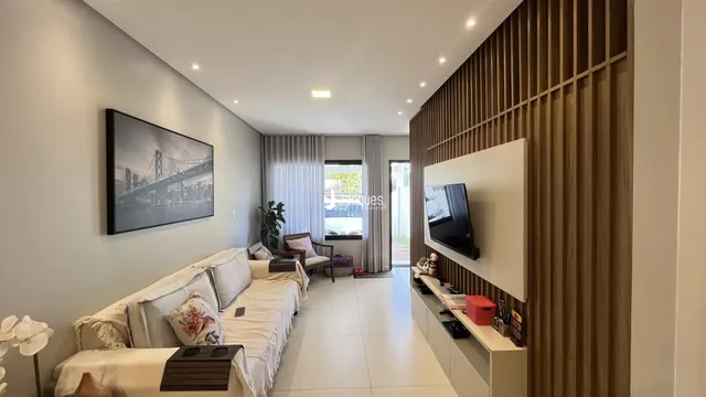 Sala de estar moderna com parede de madeira e televisão.