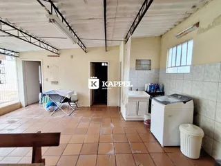 Ambiente interno com piso de cerâmica e estrutura de vigas expostas.