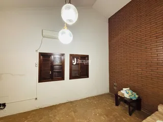 Interior de uma sala com paredes brancas e parede de tijolos aparentes.