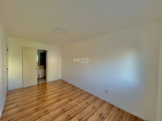 Vista interna de uma sala com piso de madeira clara.