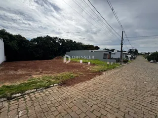 Vista externa de uma propriedade com terreno e estrada no fundo.