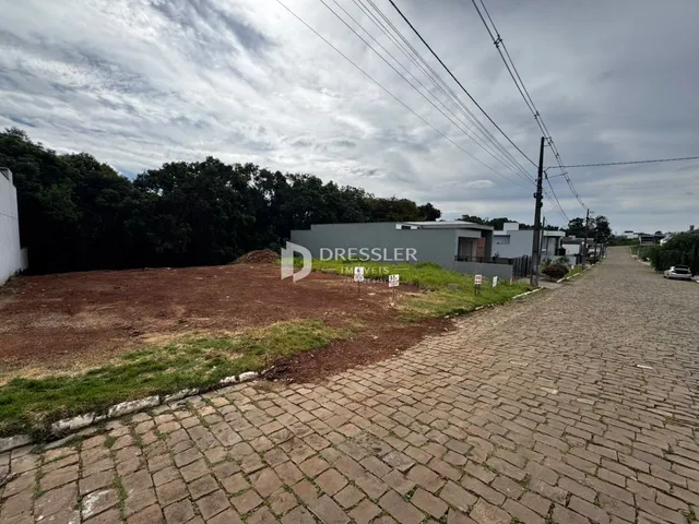 Vista externa de uma propriedade com terreno e estrada no fundo.
