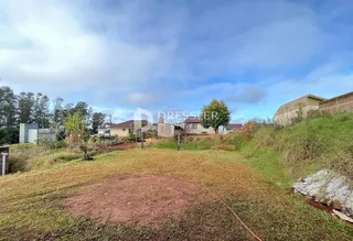 Vista externa de um terreno com grama e vegetação no primeiro plano.