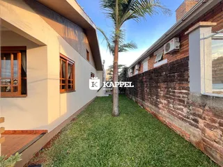 Foto da fachada de uma residência com gramado e parede de tijolos.