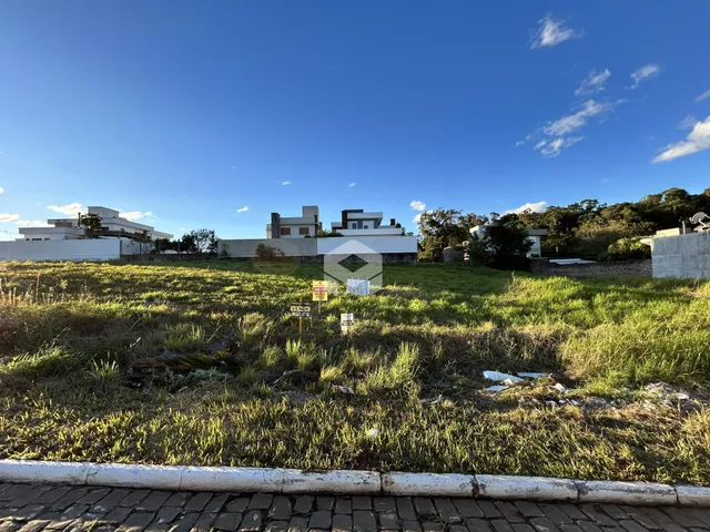 Vista externa de uma propriedade com terreno gramado e casas ao fundo.