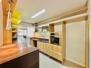 Interior de uma cozinha moderna com armários de madeira clara e bancadas.