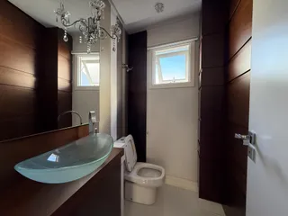 Foto de um banheiro com bancada de vidro e vaso sanitário branco.