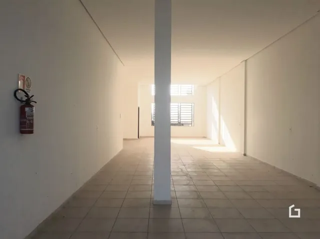 Corredor interno com paredes brancas e piso de cerâmica.