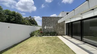 Fachada de uma residência moderna com jardim e muro branco.