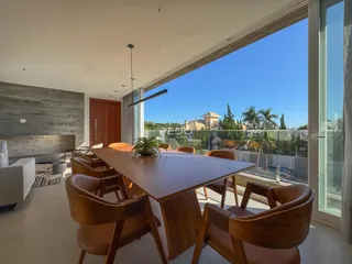 Sala de jantar com mesa de madeira e vista para a varanda.