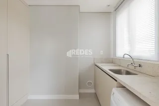 Interior de um ambiente com paredes brancas e janela com persianas.