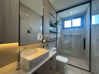 Banheiro moderno com revestimento em mármore e box de vidro.