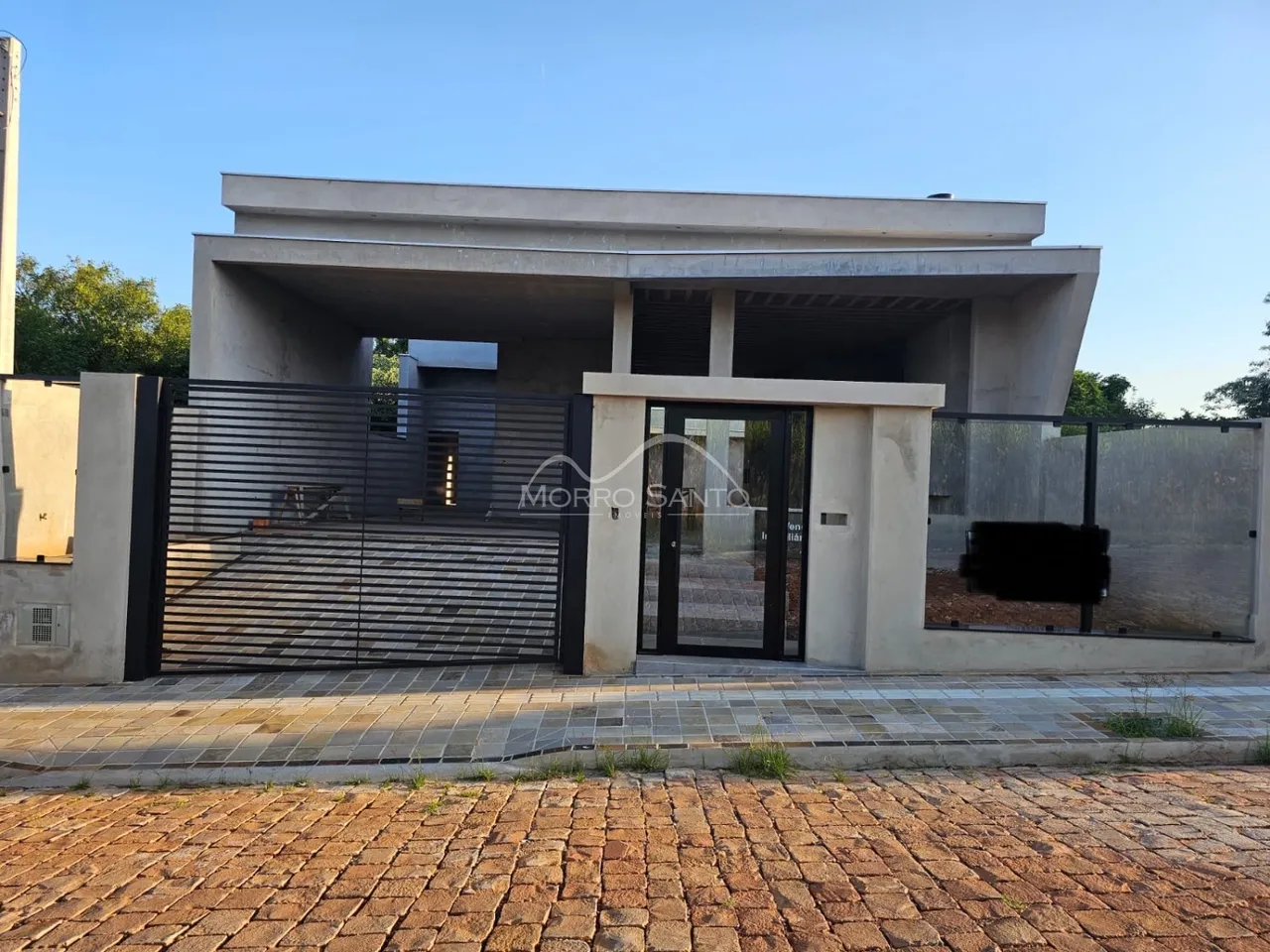 Fachada moderna de uma casa em Lajeado, Brasil, com portão de ferro e muro.