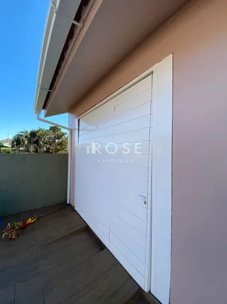 Foto da fachada de uma residência com porta branca e deck de madeira.