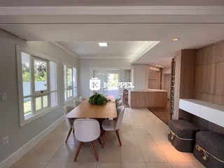Uma sala de jantar com mesa de madeira e janelas amplas.