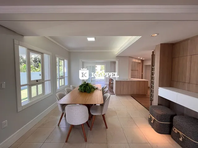 Uma sala de jantar com mesa de madeira e janelas amplas.