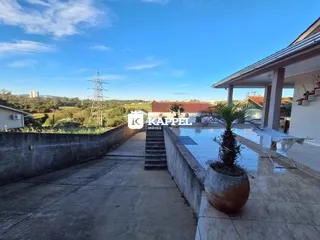 Vista externa de uma propriedade com um pátio e paisagem ao fundo.