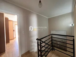 Hall de entrada com porta aberta mostrando um corredor e uma escada em um imóvel.