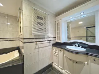 Banheiro com revestimento de cerâmica e bancada escura.